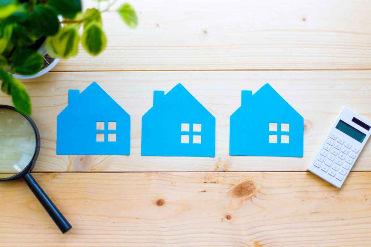 case in miniatura, lente ingrandimento e calcolatrice su superficie in legno