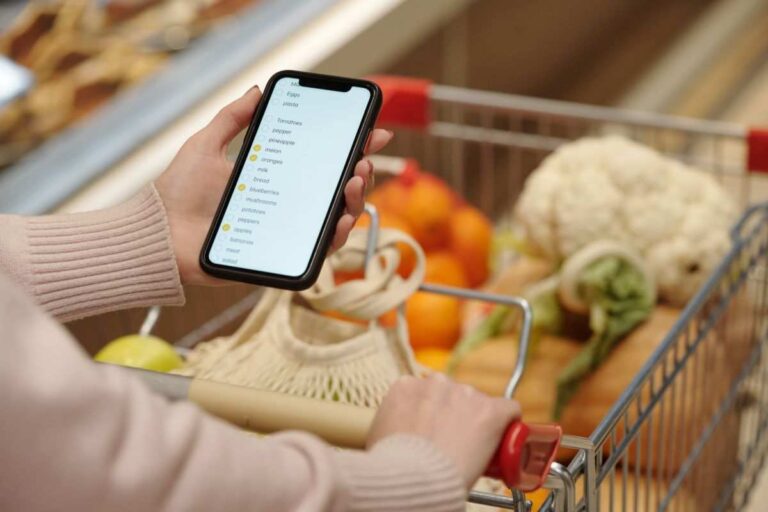 donna al supermercato con carrello e lista della spesa