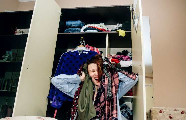 donna disperata con alle spalle armadio disordinato