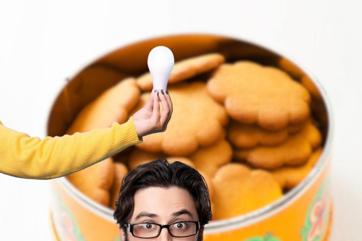 scatola di latta con biscotti e persona con idea e lampadina in mano