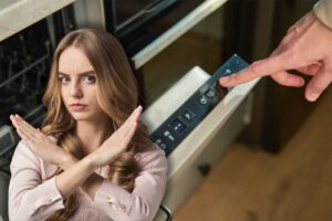 donna aziona lavastoviglie e un'altra che fa stop con le mani