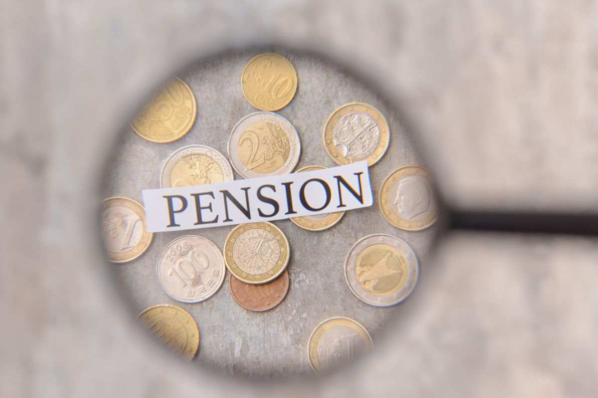 monete, scritta pensione e lente ingrandimento