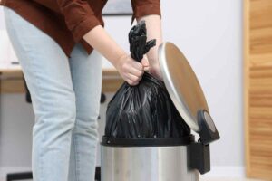donna toglie il sacco della spazzatura dal bidoncino