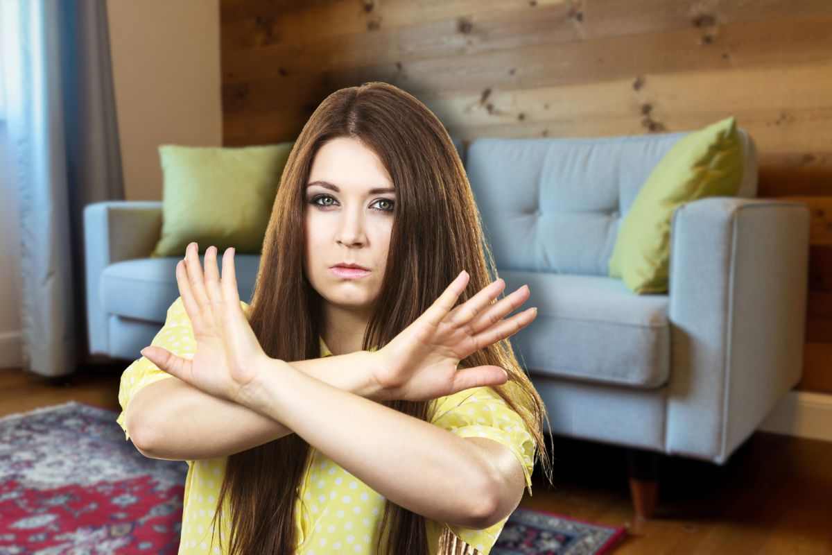 divano contro muro e donna che fa stop con le mani